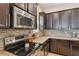 Close-up of the kitchen featuring stainless steel appliances, dark cabinets, and stone tile backsplash at 11307 Quiet Forest Dr, Tampa, FL 33635