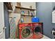 Functional laundry room with a red washer/dryer, wooden shelves, and an ironing board at 11307 Quiet Forest Dr, Tampa, FL 33635