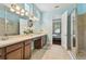 Bright bathroom featuring dual sinks, a walk-in shower, and a doorway to a bedroom at 11307 Quiet Forest Dr, Tampa, FL 33635