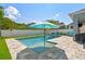 Relaxing backyard oasis featuring a sparkling pool with a sun umbrella, blue chairs, and a well-manicured lawn at 11307 Quiet Forest Dr, Tampa, FL 33635