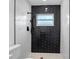 Newly renovated shower with sleek black fixtures, contrasting black tile, and clean white wavy tile accents at 1213 W Camellia Dr, Brandon, FL 33510