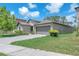 A tan single-story home featuring an attached two car garage and a well maintained green lawn at 12907 Wildflower Meadow Dr, Riverview, FL 33579