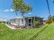 Exterior view of a white house showcasing the screened in porch and the green lawn at 14045 90Th Pl, Seminole, FL 33776