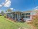 Exterior of home featuring a screened porch, adjacent to green grass and small garden at 14045 90Th Pl, Seminole, FL 33776