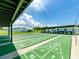 View of green shuffleboard courts with white painted game markings under covered roof at 14045 90Th Pl, Seminole, FL 33776