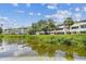 A beautiful waterfront view of condos surrounded by lush greenery reflecting on the water at 2363 Hanover Dr, Dunedin, FL 34698