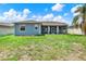 A view of the backyard shows a screened in patio and the back of the blue home at 23917 Pow Wow Dr, Lutz, FL 33559
