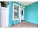 Charming front porch with vibrant turquoise exterior, white trim, and decorative door at 2715 Bel Aire Cir, Tampa, FL 33614