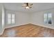 Spacious bedroom with wood-look floors, a ceiling fan, and natural light from shuttered windows at 304 Caloosa Palms Ct, Sun City Center, FL 33573