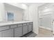A modern bathroom featuring double sinks, granite counters and a walk-in shower at 308 Mangrove Shade Cir, Apollo Beach, FL 33572