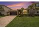 Charming single-Gathering home featuring lush landscaping, a stone facade, and a paver driveway under a beautiful sky at 3318 Woodland Brook Way, Wesley Chapel, FL 33543