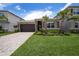 Charming single-Gathering home featuring lush landscaping, a stone facade, and a paver driveway under a sunny sky at 3318 Woodland Brook Way, Wesley Chapel, FL 33543