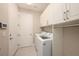 Well-lit laundry room with white cabinets, washer, dryer, and tile floors at 3318 Woodland Brook Way, Wesley Chapel, FL 33543