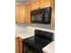 Efficient kitchen with wood cabinets, black microwave and stove-top and light countertops offering a functional cooking space at 337 S Mcmullen Booth Rd # 157, Clearwater, FL 33759
