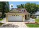 Charming, light yellow home featuring a brick paved driveway, a manicured lawn, and a white picket fence at 346 Gray Oak Dr, Tarpon Springs, FL 34689