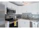 Well-lit kitchen featuring stainless steel appliances, ample white cabinetry, and granite countertops at 346 Gray Oak Dr, Tarpon Springs, FL 34689