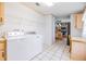 Bright laundry room with white appliances, tile floor, and convenient desk area adjacent to kitchen at 36731 Tara Ave, Zephyrhills, FL 33542