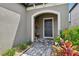 Welcoming entrance featuring a gray front door, potted plants, bench and brick paver pathway at 37820 Beacon Brick Dr, Zephyrhills, FL 33540