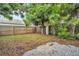 Fenced backyard featuring mature trees and a brick-paved area, perfect for outdoor living at 410 N Corona Ave, Clearwater, FL 33765
