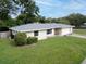 Well-kept single-story home has a spacious lawn, mature shrubs, and a two-car garage at 410 N Corona Ave, Clearwater, FL 33765