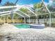 Outdoor screened pool area with spa and brick pavers, surrounded by lush greenery at 4419 W El Prado Blvd, Tampa, FL 33629