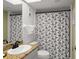 Well-lit bathroom with granite counter, patterned shower curtain, and tiled walls at 4510 Gulf Blvd # 604, St Pete Beach, FL 33706