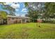 Large backyard with green grass, shed, trees, and the back of the home at 5700 Pacific N St, St Petersburg, FL 33703