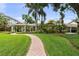 Charming single-story home with lush landscaping, brick walkway, and tropical palm trees in the front yard at 648 Geneva Pl, Tampa, FL 33606