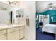 Well-lit bathroom with cream cabinets and a double mirror reflecting into a blue bedroom, creating a bright aesthetic at 6801 Summer Cove Dr, Riverview, FL 33578