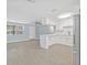 Open-concept kitchen with white cabinets, gray tile flooring, and view of the front door at 6807 River Rd, Tampa, FL 33615