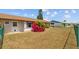 View of backyard showing house, flowerbeds, and fenced yard with a manicured lawn at 828 Fox Hills Dr, Sun City Center, FL 33573