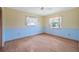 Bright bedroom with two windows, light yellow walls, and blue trim offers plenty of natural light and space at 828 Fox Hills Dr, Sun City Center, FL 33573