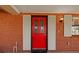 Inviting front entrance with brick siding, covered porch, stylish shutters, and vibrant red front door at 828 Fox Hills Dr, Sun City Center, FL 33573