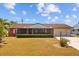 Charming single-story home with manicured landscaping, mature trees, and a vibrant red front door at 828 Fox Hills Dr, Sun City Center, FL 33573
