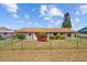 Charming ranch-style home with a well-manicured lawn and mature landscaping, complemented by a green chain-link fence at 828 Fox Hills Dr, Sun City Center, FL 33573