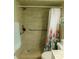 Accessible walk-in shower featuring neutral tile, grab bars, and a colorful shower curtain at 9 Forbes Pl # 310, Dunedin, FL 34698