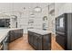 Open kitchen featuring a large island, dark cabinetry, stainless steel appliances, and hardwood floors at 9712 Tree Tops Lake Rd, Tampa, FL 33626