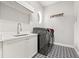 Modern laundry room with stylish patterned floors, sink, and a new washer and dryer at 9712 Tree Tops Lake Rd, Tampa, FL 33626
