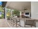 Outdoor kitchen and bar seating overlooks a lake, complete with a fireplace and television at 9712 Tree Tops Lake Rd, Tampa, FL 33626