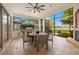 Covered outdoor dining area with a fireplace, ceiling fan, and outdoor kitchen space overlooking the lake at 9712 Tree Tops Lake Rd, Tampa, FL 33626
