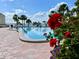 A relaxing community pool with a brick patio is surrounded by lush flowers and tropical palm trees at 100 Bluff View Dr # 115C, Belleair Bluffs, FL 33770