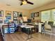 The art studio features paintings and multiple work tables under a ceiling fan and natural light at 100 Bluff View Dr # 115C, Belleair Bluffs, FL 33770