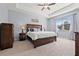 Comfortable bedroom featuring a tray ceiling, wood furniture, a large window, and neutral carpet at 11434 Leland Groves Dr, Riverview, FL 33579