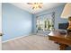 Well-lit room with neutral carpet, large window, blue walls and a wooden desk at 11434 Leland Groves Dr, Riverview, FL 33579