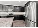 Close-up of kitchen with stainless steel refrigerator, granite countertops, and dark cabinetry at 11434 Leland Groves Dr, Riverview, FL 33579