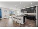 Modern kitchen featuring dark cabinetry, granite countertops, stainless steel appliances, and wood-look flooring at 11434 Leland Groves Dr, Riverview, FL 33579