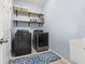 Laundry room featuring blue walls, front-load machines, and open storage shelves at 11434 Leland Groves Dr, Riverview, FL 33579