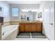 Bathroom featuring a garden tub, double sink vanity, granite countertops, tile flooring, and a private toilet room at 11614 Ashton Field Ave, Riverview, FL 33579