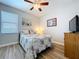 Bedroom with wood floor, ceiling fan, with a bed, dresser with mounted tv above and an adjacent window at 11614 Ashton Field Ave, Riverview, FL 33579