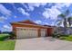 Charming single-story home with a three-car garage, well-maintained landscaping, and an orange painted stucco facade at 11614 Ashton Field Ave, Riverview, FL 33579